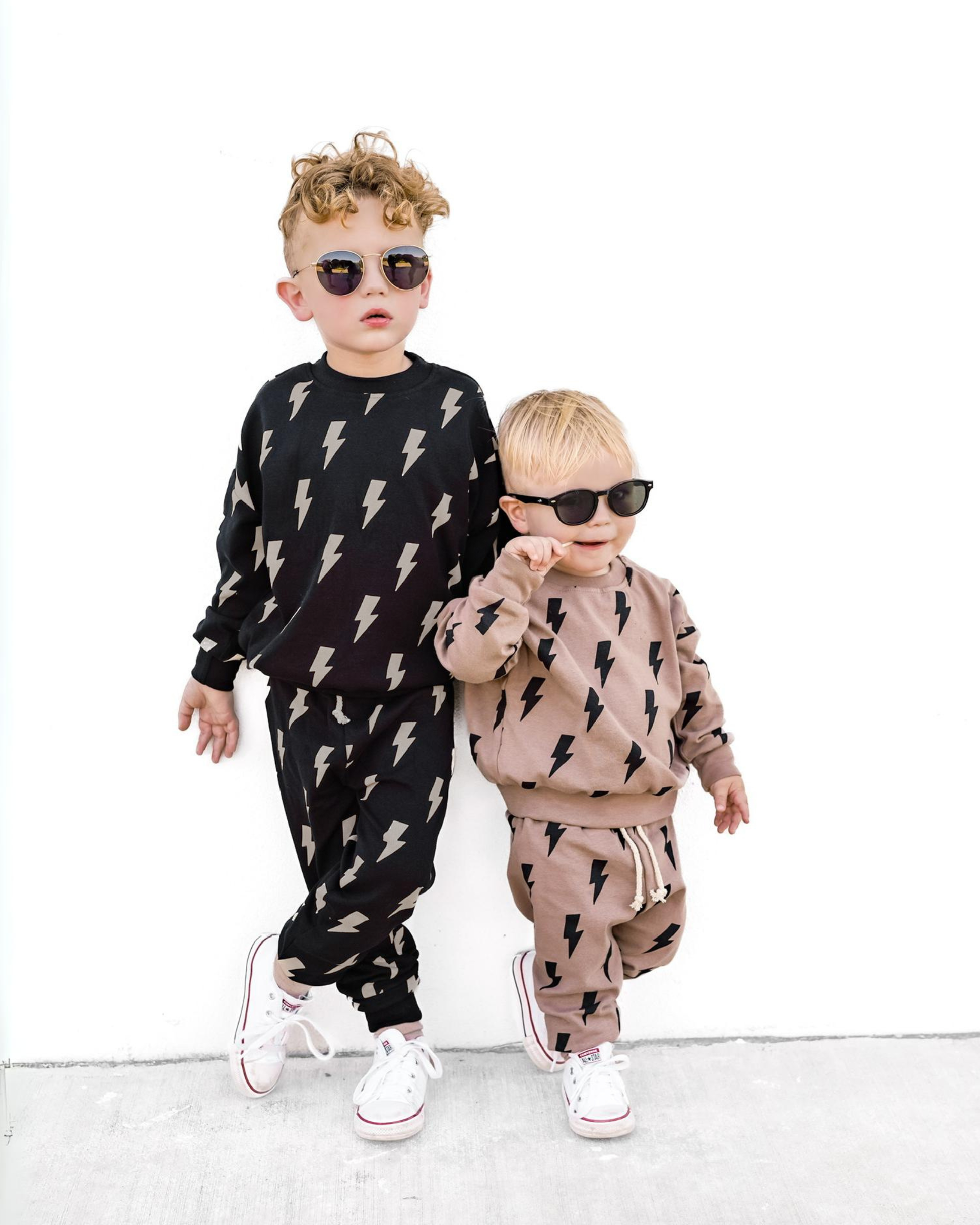 Two children wearing matching outfits with lightning bolt patterns on a white background